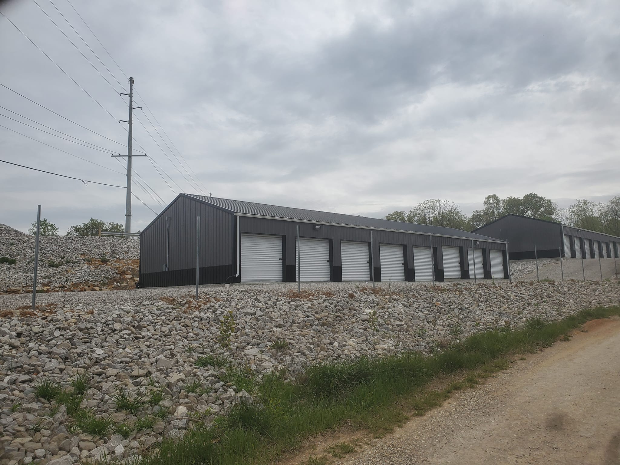 A fenced in storage unit building with 8 units each having an overhead door.